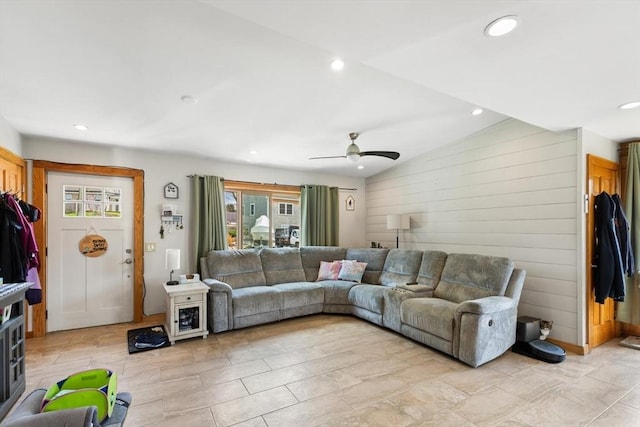 living area with lofted ceiling, recessed lighting, a ceiling fan, and wooden walls