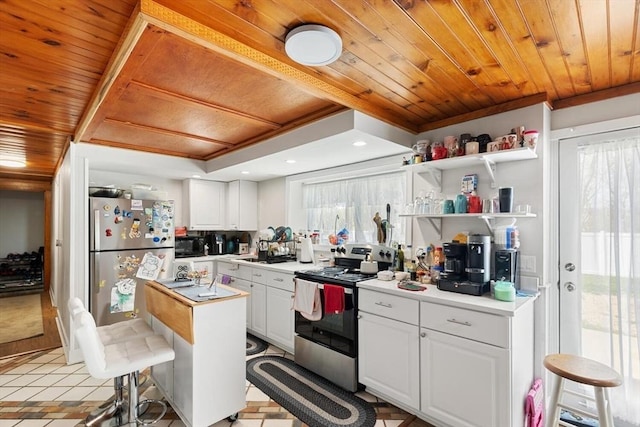 kitchen with appliances with stainless steel finishes, wooden ceiling, healthy amount of natural light, white cabinetry, and light countertops
