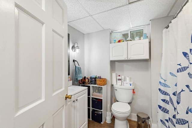 bathroom featuring a paneled ceiling, toilet, vanity, baseboards, and a shower with curtain