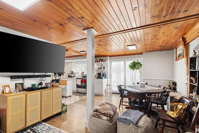 dining area with wooden ceiling, a wainscoted wall, light wood finished floors, and ornate columns