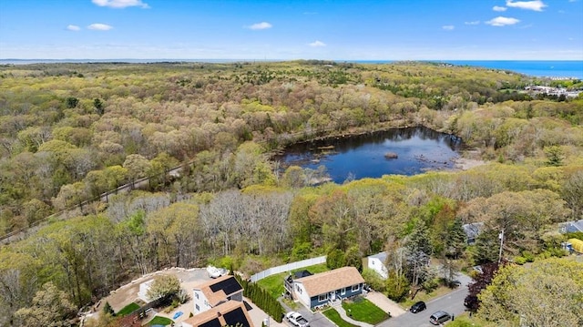 aerial view of property and surrounding area featuring a heavily wooded area and a large body of water