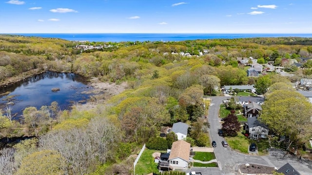 aerial view of property's location featuring a heavily wooded area, a nearby body of water, and nearby suburban area