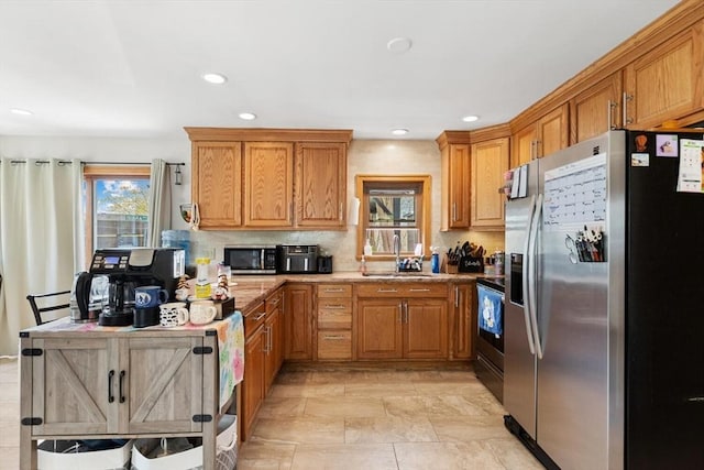 kitchen featuring appliances with stainless steel finishes, a sink, brown cabinets, and recessed lighting
