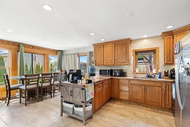 kitchen featuring a sink, appliances with stainless steel finishes, brown cabinetry, and recessed lighting