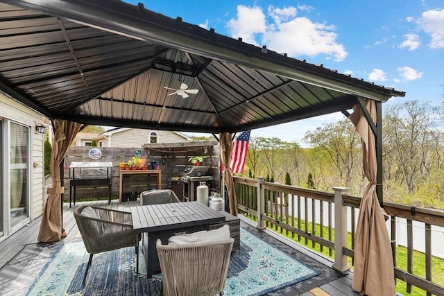 wooden deck featuring a gazebo, ceiling fan, outdoor dining area, and fence