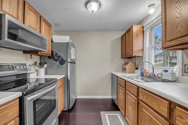 kitchen with a textured ceiling, stainless steel appliances, dark hardwood / wood-style floors, and sink