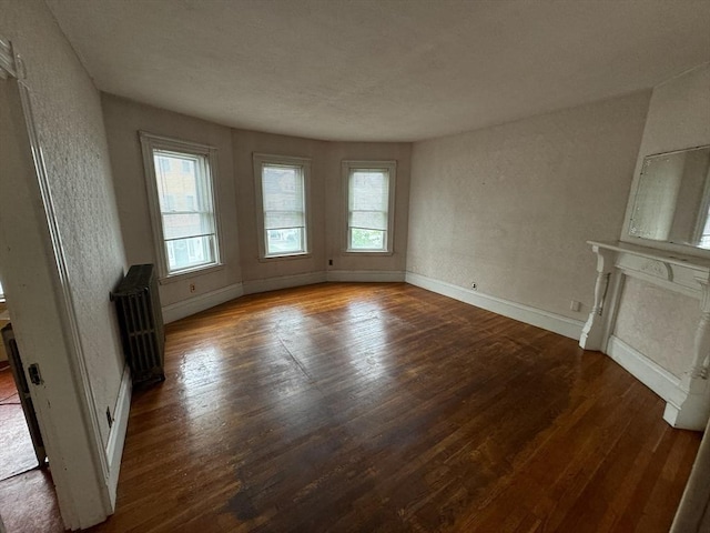 915 E 4th St, Boston, MA 02127 - unfurnished living room featuring radiator heating unit, wood finished floors, baseboards, a textured wall, and a fireplace