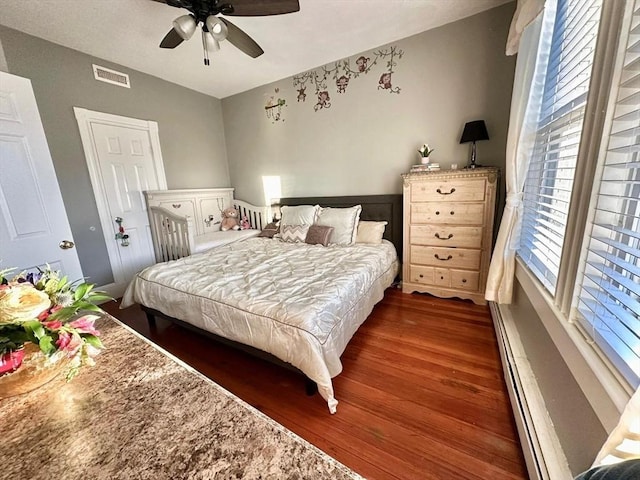 bedroom with dark wood-type flooring, a baseboard radiator, and ceiling fan