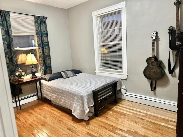bedroom with baseboard heating and wood finished floors