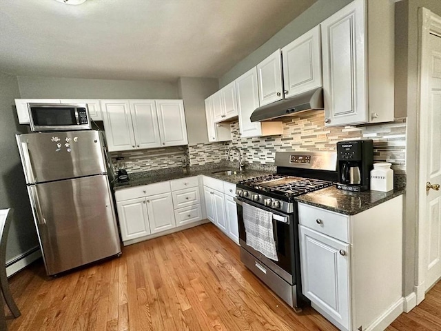 kitchen with appliances with stainless steel finishes, under cabinet range hood, a sink, and white cabinetry