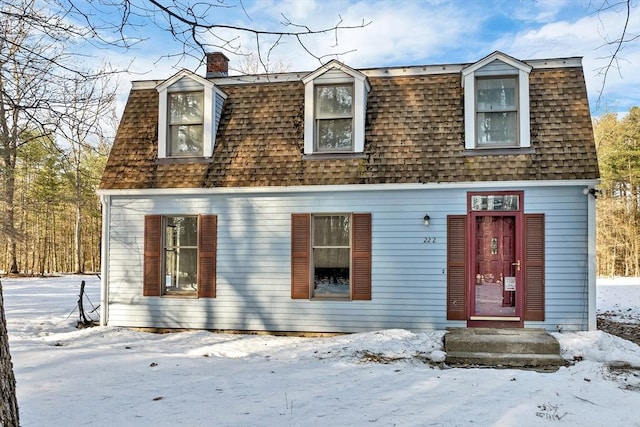 colonial inspired home featuring a chimney and a shingled roof