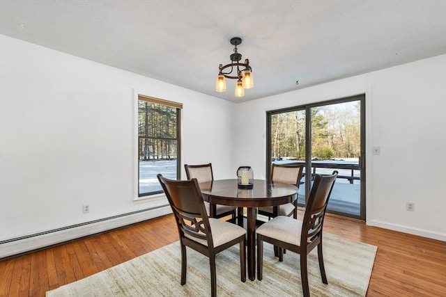 dining area featuring a wealth of natural light, a baseboard radiator, a notable chandelier, and light wood finished floors