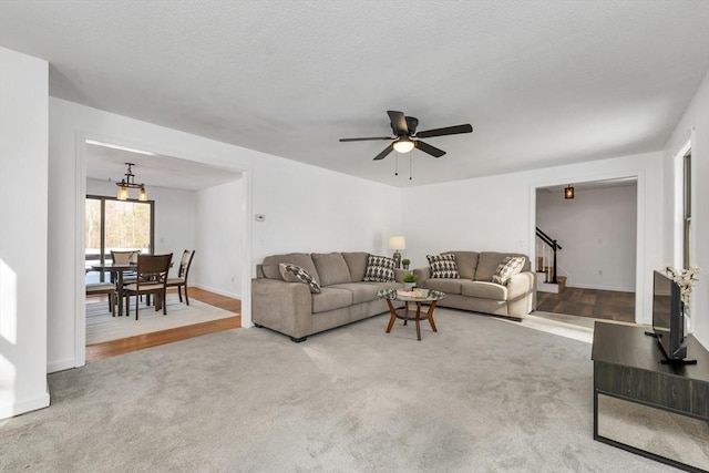 carpeted living area featuring stairway, baseboards, and a textured ceiling