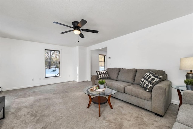 carpeted living area with baseboards and a ceiling fan