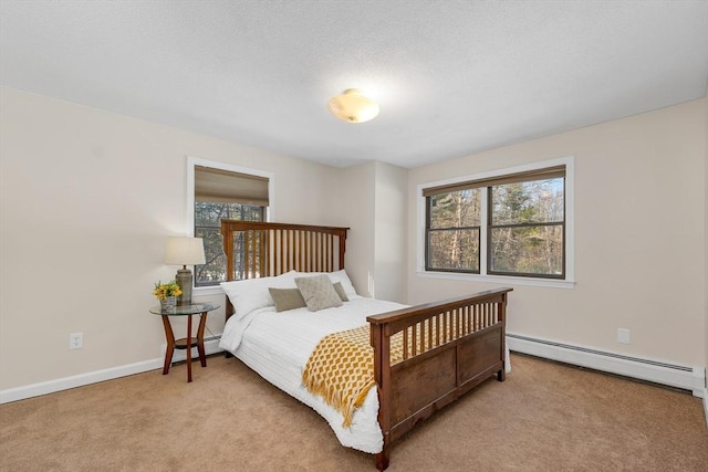 bedroom featuring multiple windows, a baseboard heating unit, baseboards, and carpet floors