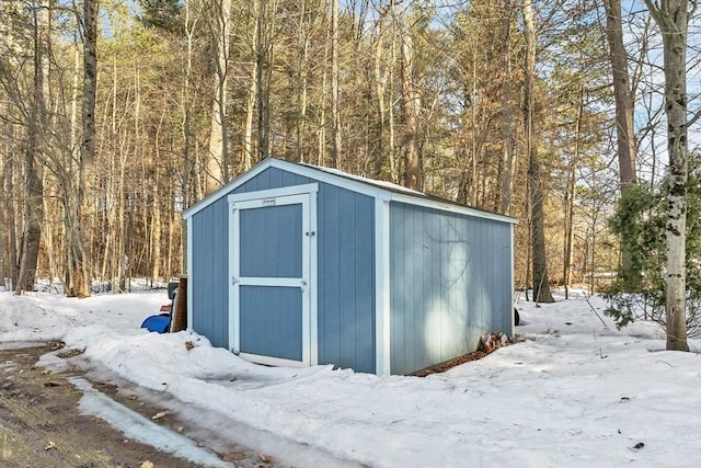 snow covered structure featuring a storage shed and an outdoor structure