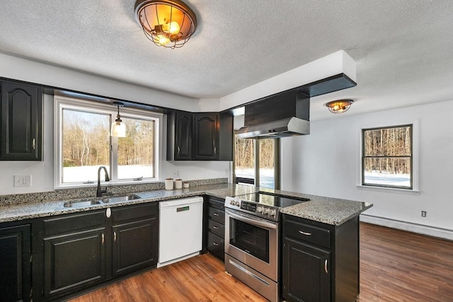 kitchen featuring wall chimney range hood, dishwasher, stainless steel range with electric stovetop, dark cabinetry, and a sink