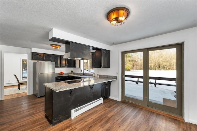 kitchen with dark wood-type flooring, a baseboard heating unit, black electric stovetop, a peninsula, and freestanding refrigerator