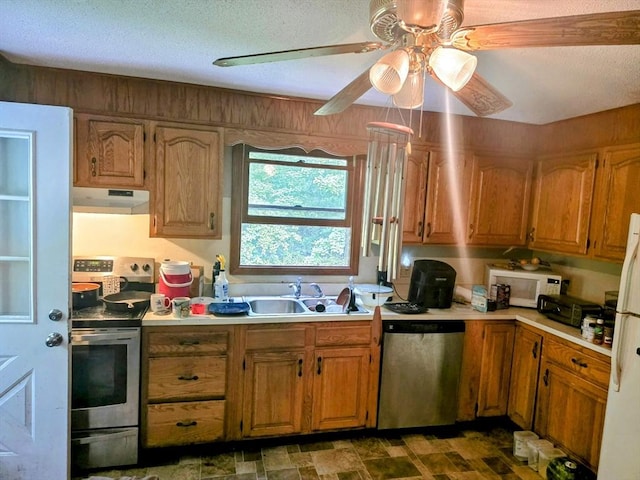 209-211 Ventura St, Ludlow, MA 01056 - kitchen featuring appliances with stainless steel finishes, under cabinet range hood, ceiling fan, light countertops, and brown cabinetry