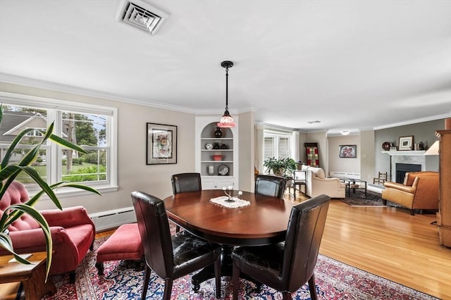 64 Pond St, Nahant, MA 01908 - dining space with ornamental molding, wood finished floors, a baseboard radiator, a fireplace, and built in features