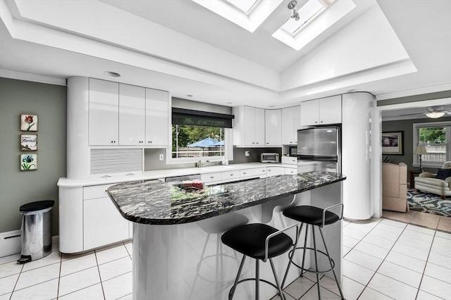 64 Pond St, Nahant, MA 01908 - kitchen with a kitchen bar, light tile patterned flooring, a tray ceiling, and white cabinetry