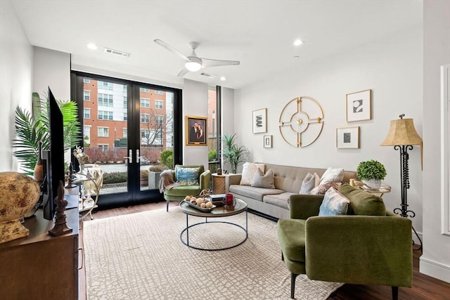 living room featuring wood-type flooring, french doors, ceiling fan, and a wall of windows