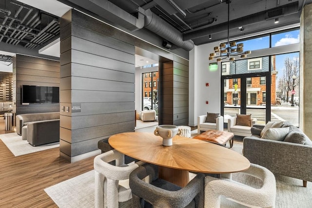 dining area featuring a towering ceiling, hardwood / wood-style floors, a notable chandelier, and wooden walls