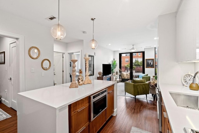 kitchen with dark wood-type flooring, sink, decorative light fixtures, a center island, and expansive windows