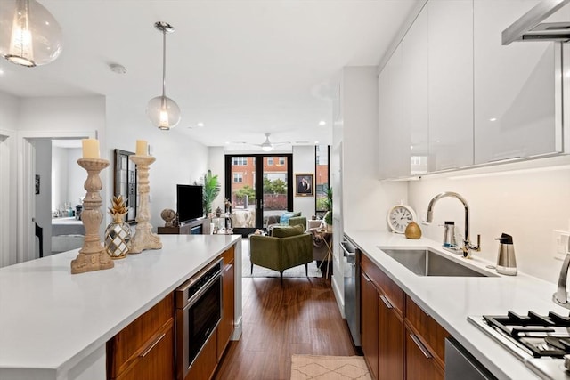 kitchen featuring sink, dishwasher, white cabinetry, dark hardwood / wood-style floors, and decorative light fixtures