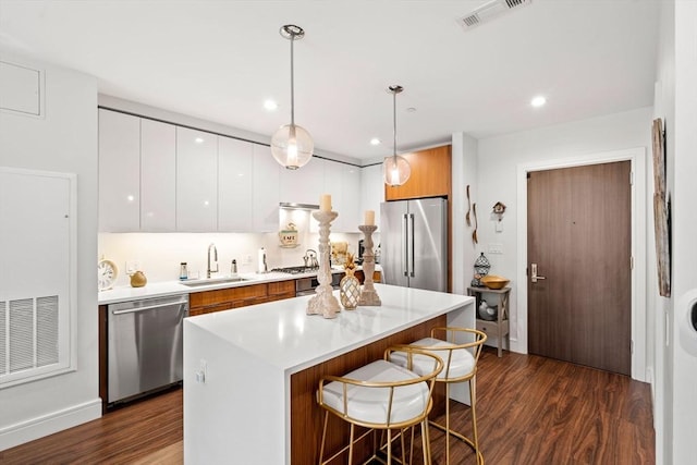 kitchen with pendant lighting, sink, white cabinets, dark hardwood / wood-style flooring, and stainless steel appliances