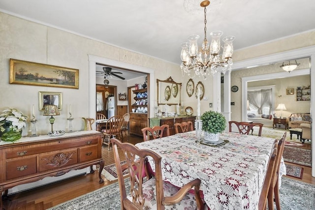 dining space with dark wood-style flooring, crown molding, a chandelier, and ceiling fan
