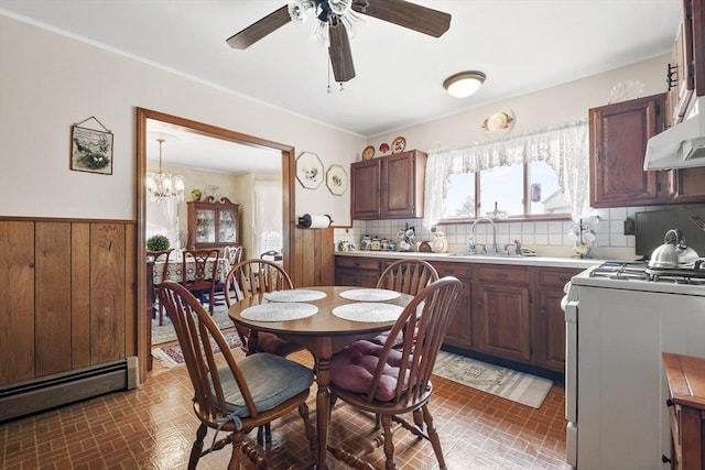 kitchen featuring white gas range oven, a sink, brick patterned floors, ceiling fan, and a baseboard radiator