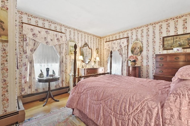 bedroom featuring wallpapered walls, a baseboard heating unit, and wood finished floors