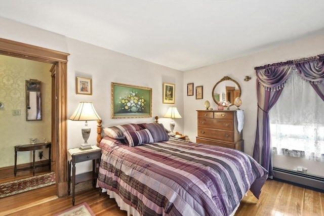 bedroom featuring wood finished floors and a baseboard heating unit