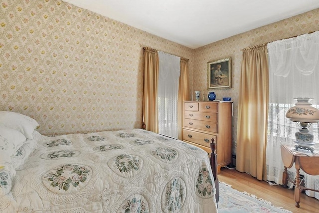 bedroom with wallpapered walls and light wood-style flooring