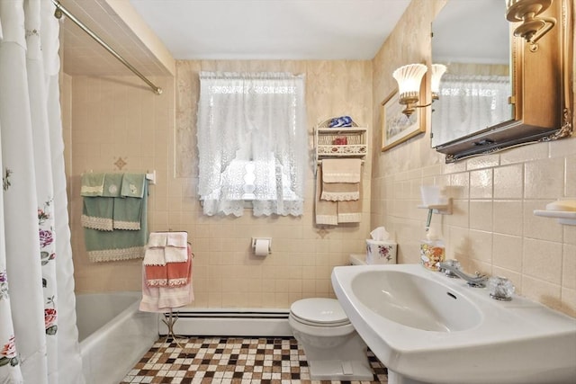 full bathroom with a baseboard heating unit, tile walls, toilet, shower / bathtub combination with curtain, and a sink