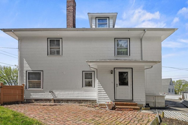 view of front of home featuring entry steps, fence, a chimney, and a patio area