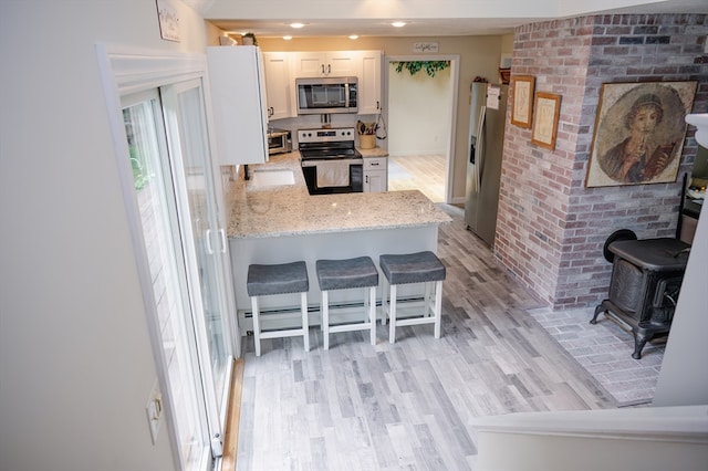 kitchen featuring appliances with stainless steel finishes, light hardwood / wood-style floors, white cabinets, and kitchen peninsula