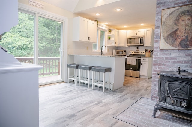 kitchen with appliances with stainless steel finishes, light hardwood / wood-style flooring, a healthy amount of sunlight, and white cabinetry