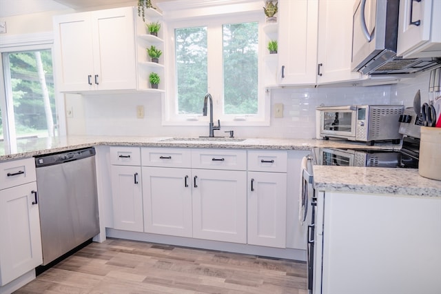 kitchen with appliances with stainless steel finishes, backsplash, sink, light wood-type flooring, and white cabinets