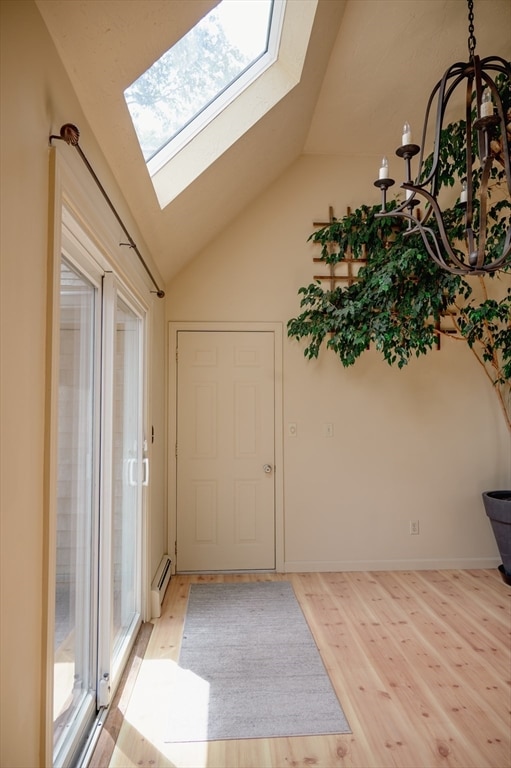 foyer entrance with vaulted ceiling with skylight and light hardwood / wood-style flooring