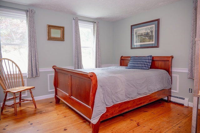 bedroom with light hardwood / wood-style flooring and a baseboard radiator