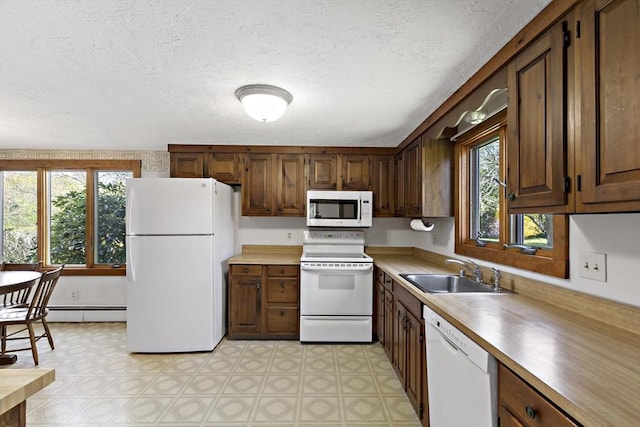 kitchen with white appliances, a textured ceiling, a sink, and light floors