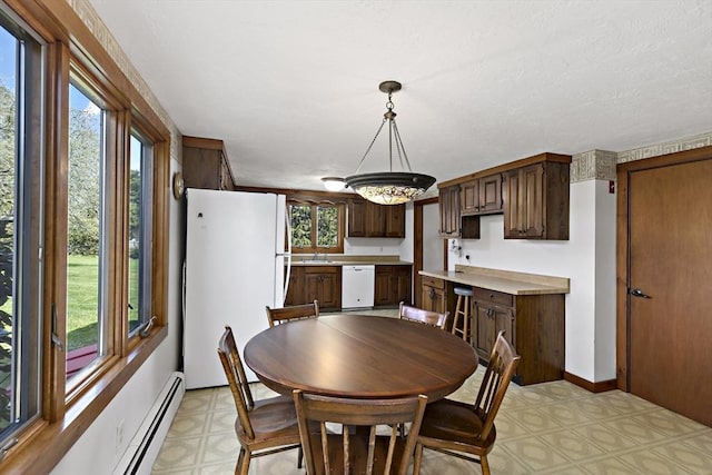 dining area with an inviting chandelier, a baseboard radiator, a wealth of natural light, and light floors