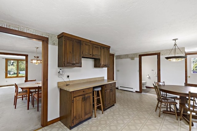 kitchen with decorative light fixtures, baseboard heating, light countertops, an inviting chandelier, and light floors