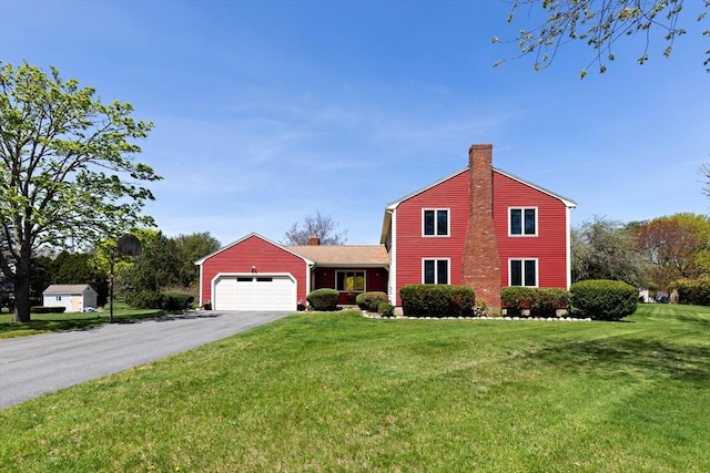 view of front of house with an attached garage, driveway, a chimney, and a front lawn