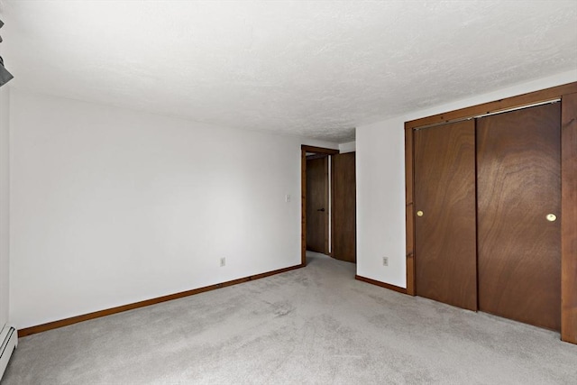 unfurnished bedroom with baseboards, a baseboard heating unit, light carpet, and a closet