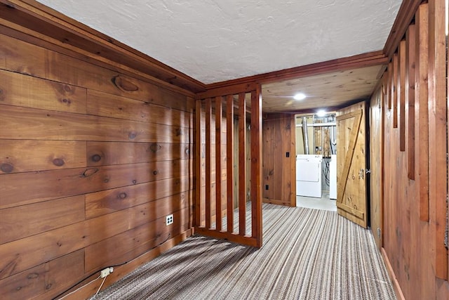 interior space with carpet floors, wood walls, a textured ceiling, and washer and clothes dryer