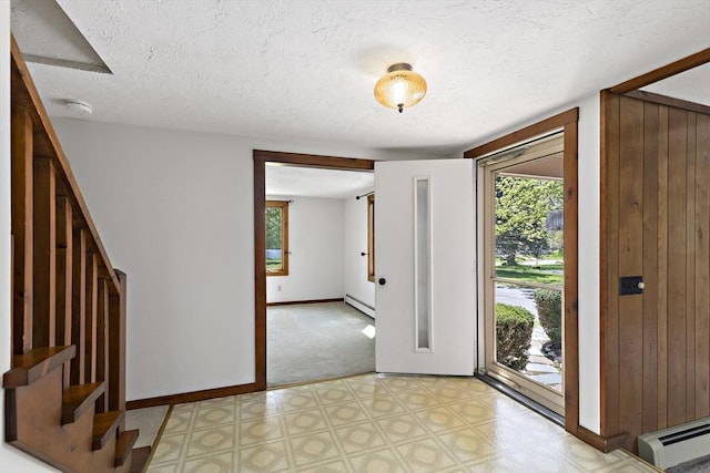 foyer featuring baseboards, a textured ceiling, light floors, and a baseboard heating unit
