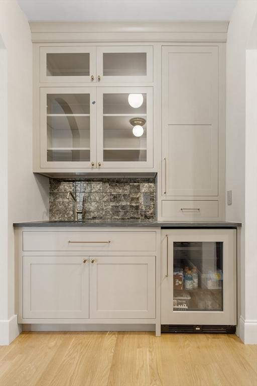 bar with white cabinets, light hardwood / wood-style floors, beverage cooler, and decorative backsplash